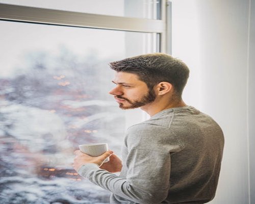 Person relaxing holding a cup of tea near a window